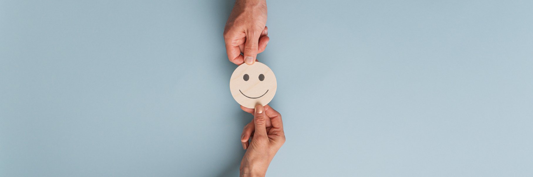 Male and Female Hands Holding a Smiley Face on Paper